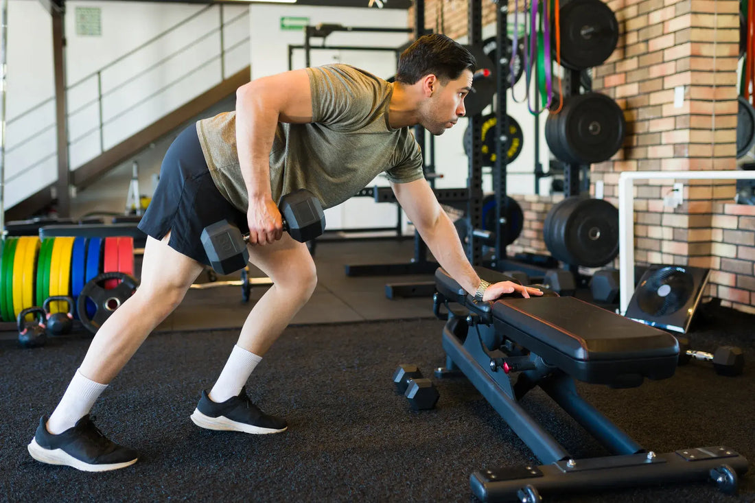 Person performing a dumbbell row with correct form in a gym setting, demonstrating proper strength training technique.